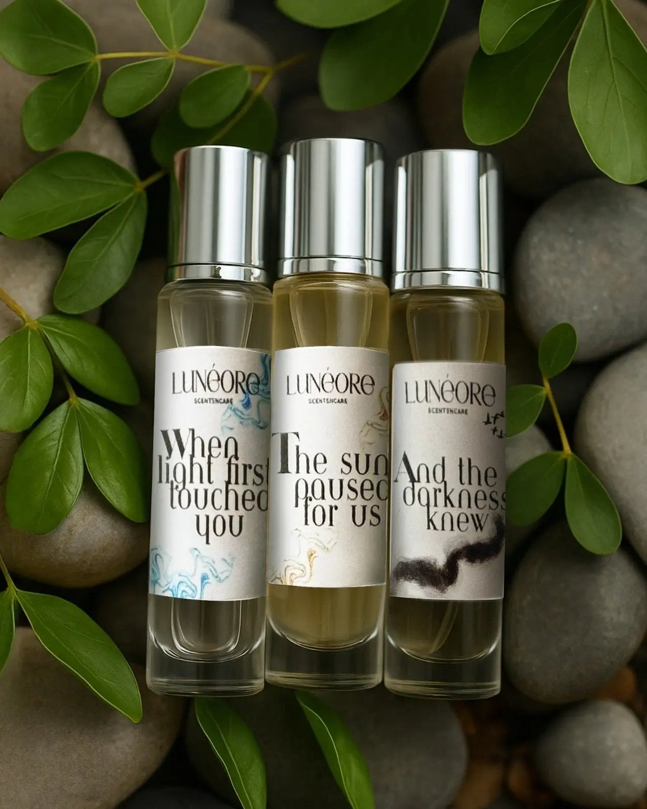 Three perfume bottles with labels on a stone surface with leaves